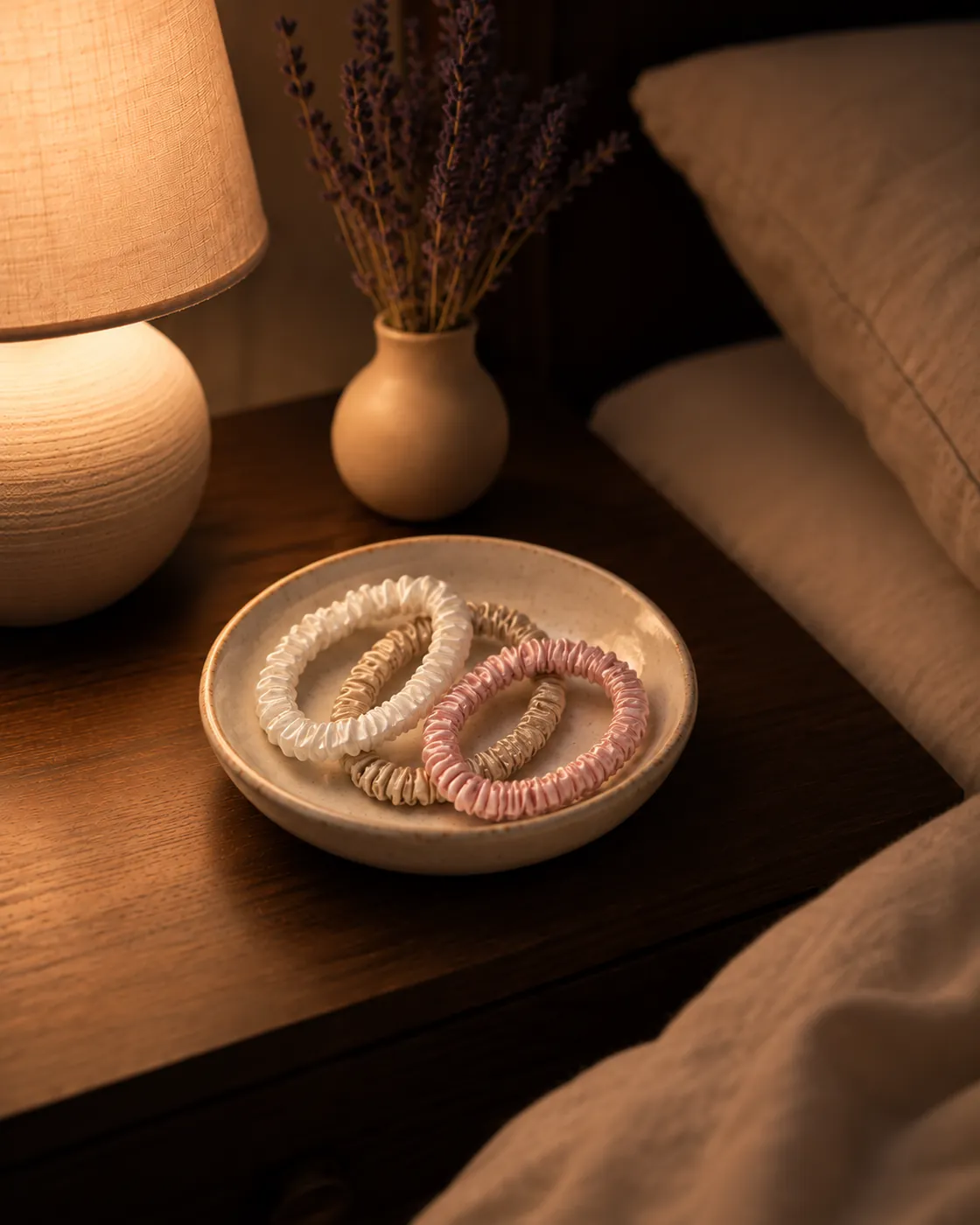 Silk scrunchies in a ceramic dish on a nightstand